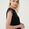 prim-plan cu banda contrastantă albă oblică și fenta laterală a rochiei negre