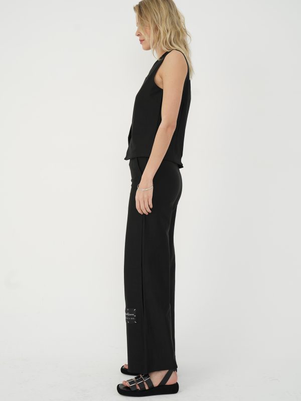 din profil, set negru cu vestă fără mâneci și pantaloni cu croială largă