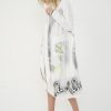look de primăvară cu trenci alb ușor cu imprimeu grafic peste o rochie
