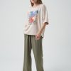 din profil, tricou oversized bej cu croială lejeră și imprimeu abstract