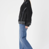 vedere din lateral, femeie purtând o bluză neagră cu buzunare și jeans