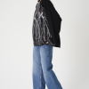 femeie purtând o bluză oversized neagră cu print artistic și jeans