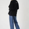 vedere din spate, femeie purtând o bluză oversized neagră cu print artistic și jeans