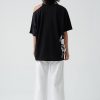 femeie purtând un tricou oversize negru cu decupaj și pantaloni albi
