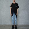 femeie purtând un tricou asimetric negru cu umăr decupat și blugi