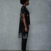 femeie purtând un set urban negru cu bluză asimetrică și pantaloni conici cu cizme cu toc negre